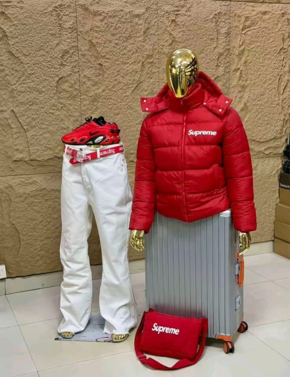 Red Supreme puffer jacket paired with white baggy pants on mannequin.