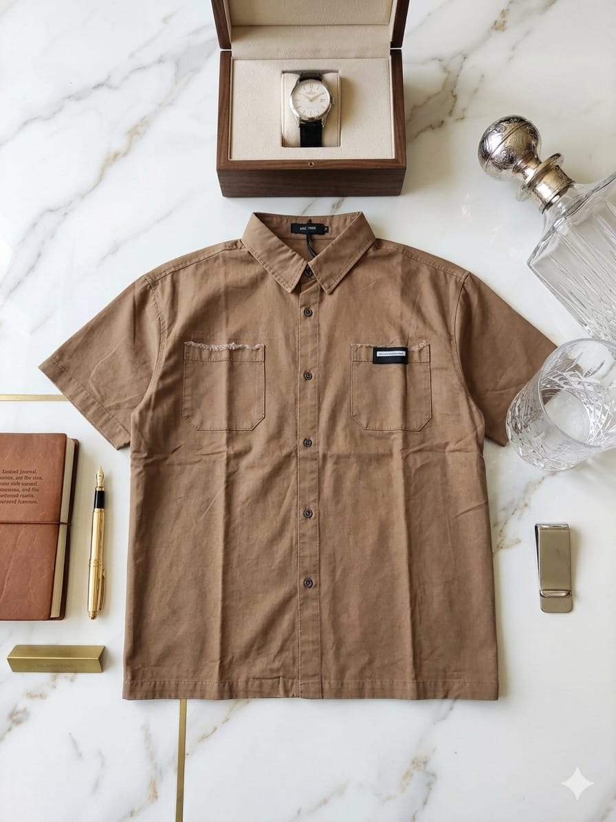Brown short sleeve button-up shirt with two chest pockets styled on marble surface with accessories.