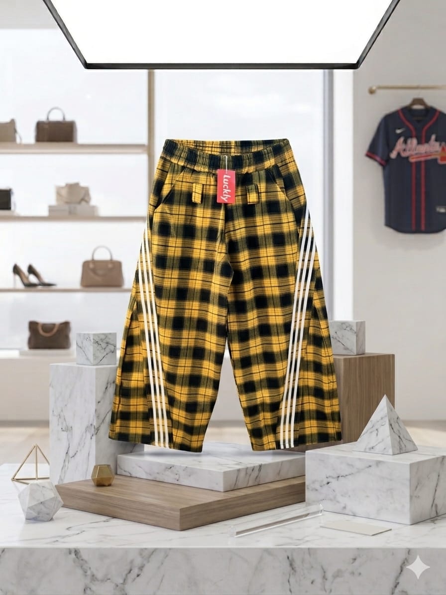 Yellow and black plaid joggers displayed on marble pedestal in studio.