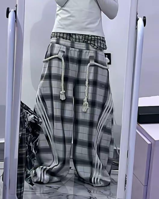 Model wearing gray plaid joggers with white stripes and drawstring.