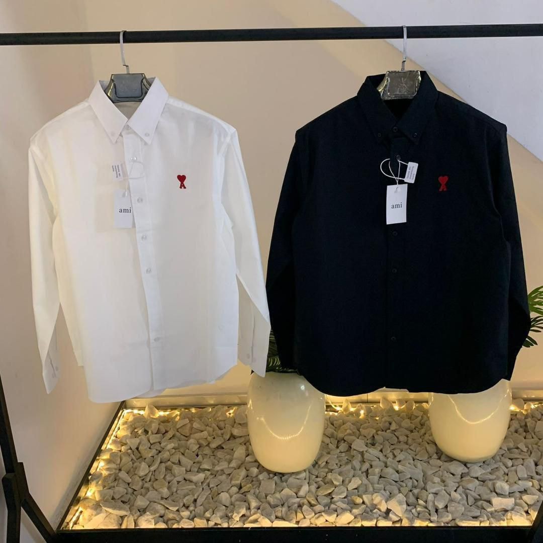 White and black long sleeve button-down shirts with red chest embroidery on display
