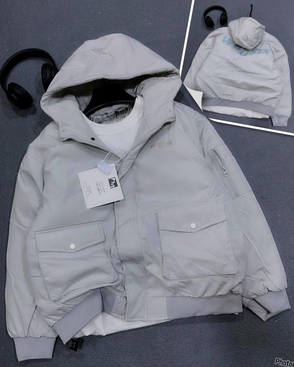 Gray hooded puffer jacket with cargo pockets, hood, and embroidery details.