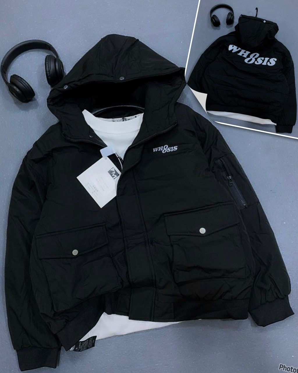 Black hooded puffer jacket with cargo pockets, hood, and chest embroidery.