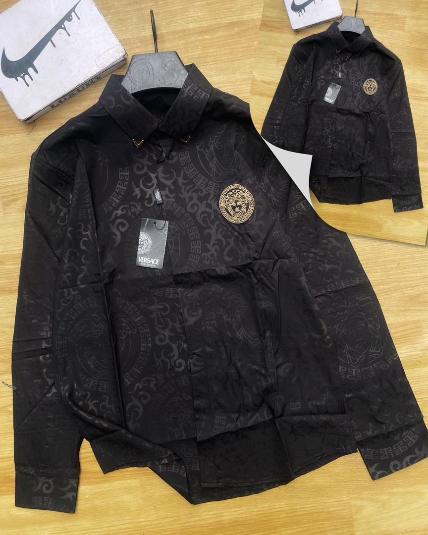 Black Versace all-over print long sleeve shirt on wooden surface with tags and packaging.