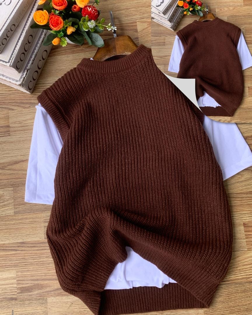 Brown ribbed knit armless cardigan layered over white t-shirt on wooden surface.