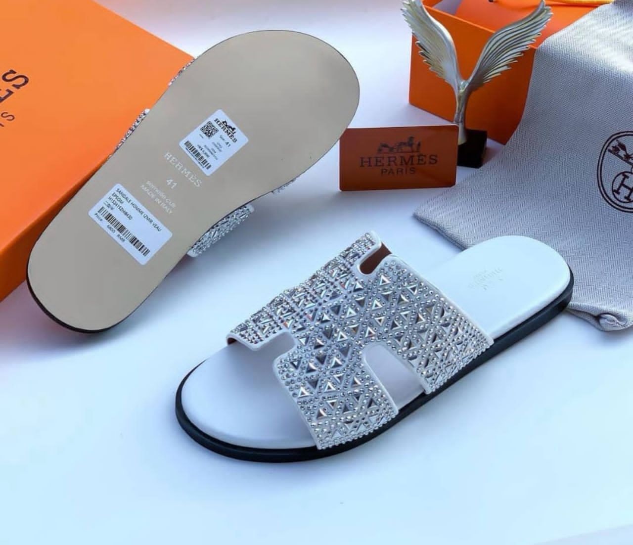 White Hermes slide sandal with silver rhinestone and stud details on the strap, shown with original box, dust bag and accessories.