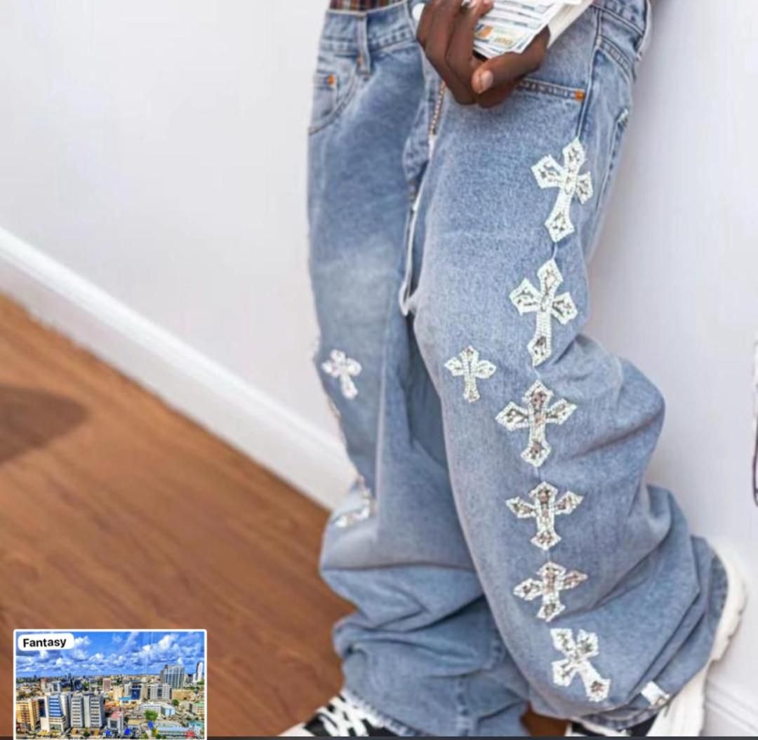 Person wearing light blue baggy jeans with white cross embroidery on the leg.