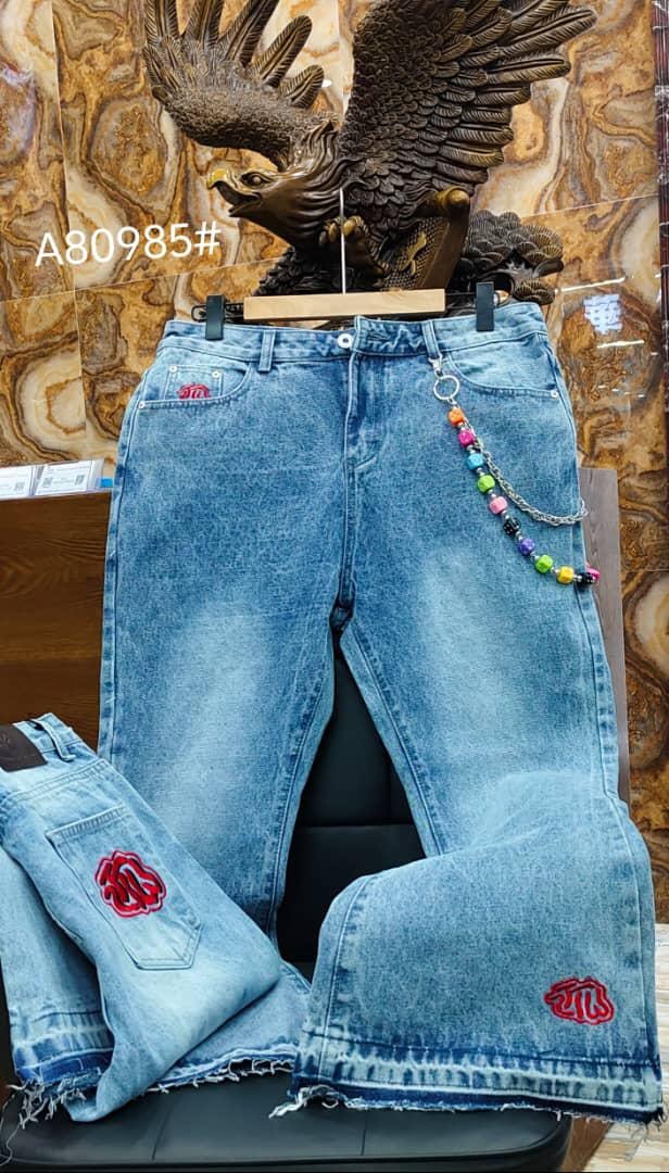 Alternate angle of light blue baggy jeans showing rose embroidery and chain accessory.