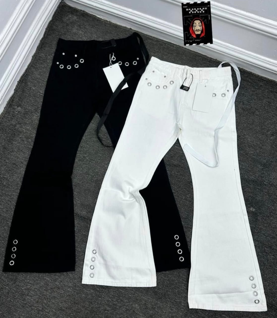 Black and white baggy flared jeans with silver eyelet details displayed side by side.