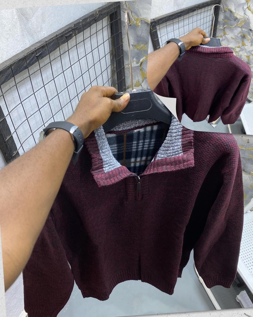 Burgundy textured knit quarter-zip sweatshirt held on hanger showing collar and fabric texture.