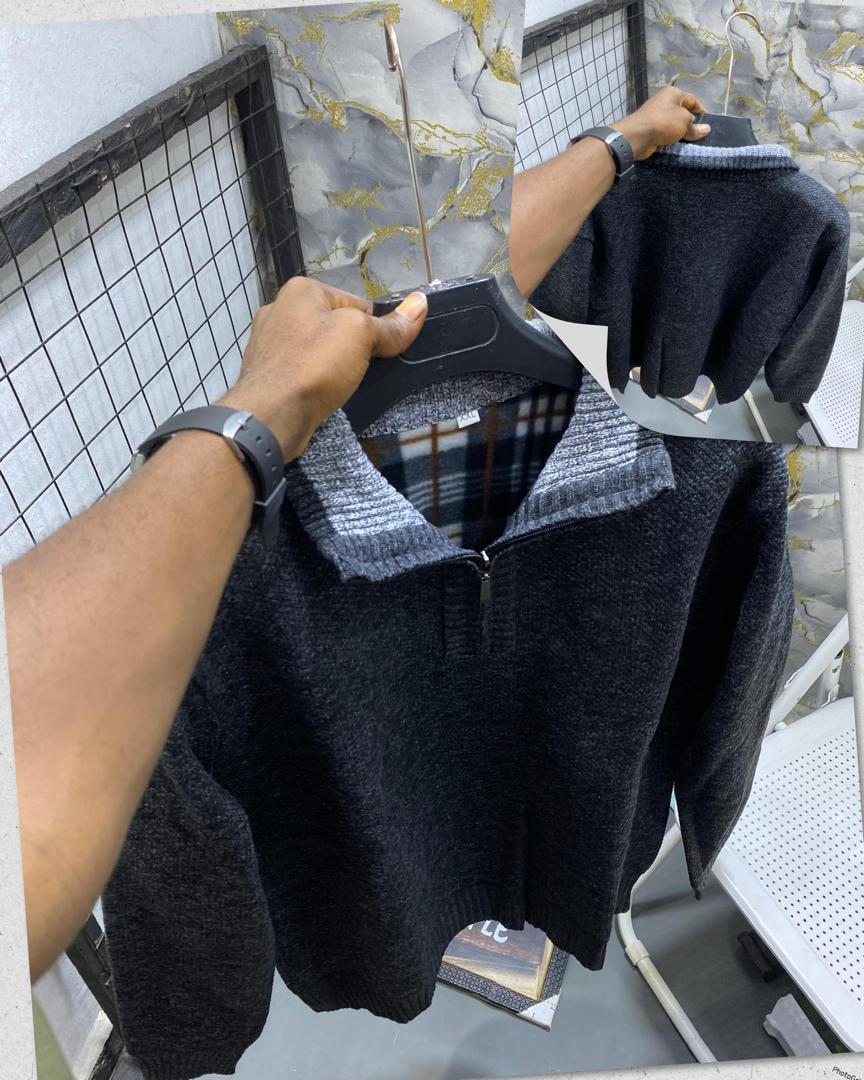 Black textured knit quarter-zip sweatshirt on hanger revealing plaid interior and ribbed details.