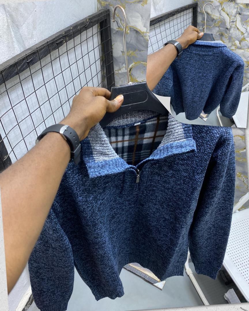 Blue textured knit quarter-zip sweatshirt on hanger showing collar detail and interior lining.