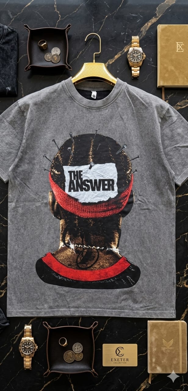 Stonewashed gray t-shirt with head and pins graphic plus THE ANSWER note, styled with watches, trays and notebook on dark marble.