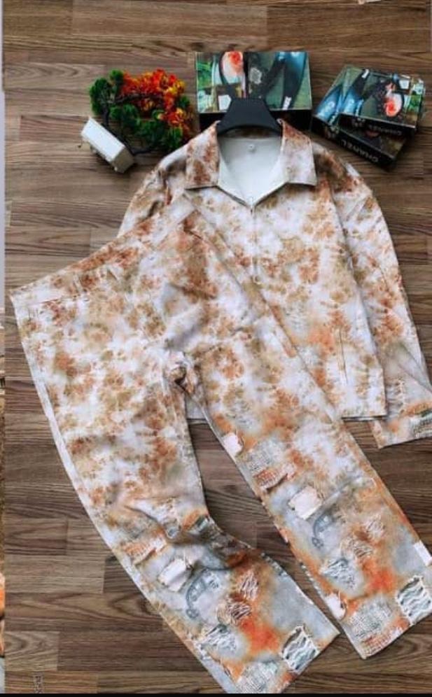 Orange bleached and distressed print shirt and pants two-piece set on wooden surface.