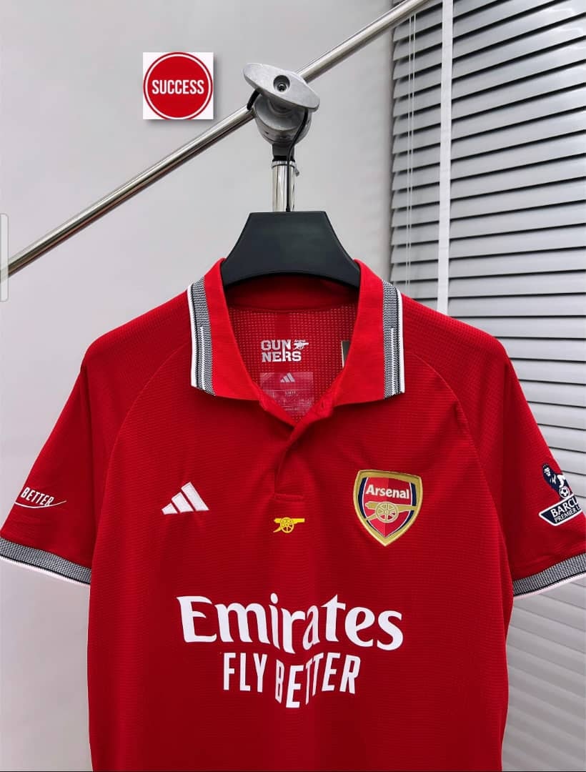 Red Arsenal polo jersey featuring club crest and sponsor text.