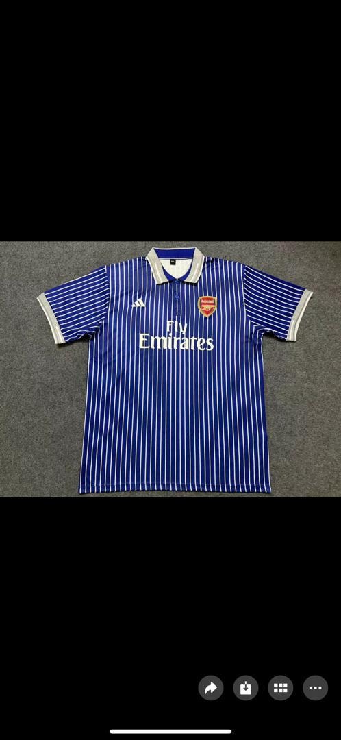 Blue and white striped Adidas Arsenal Fly Emirates polo shirt laid flat.