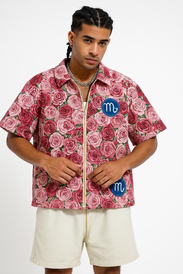 Man wearing pink rose print zip-up crop shirt with blue logo patches.