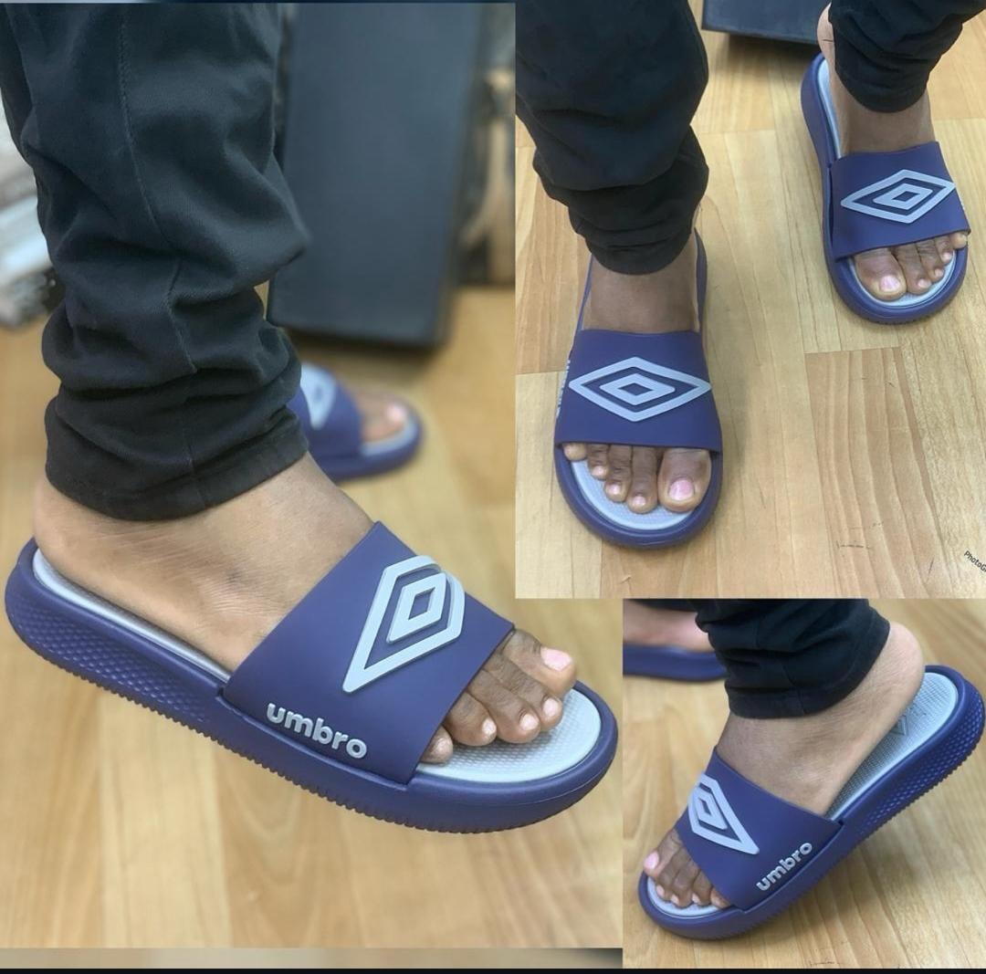 Navy Umbro slides from various angles on a wooden floor.