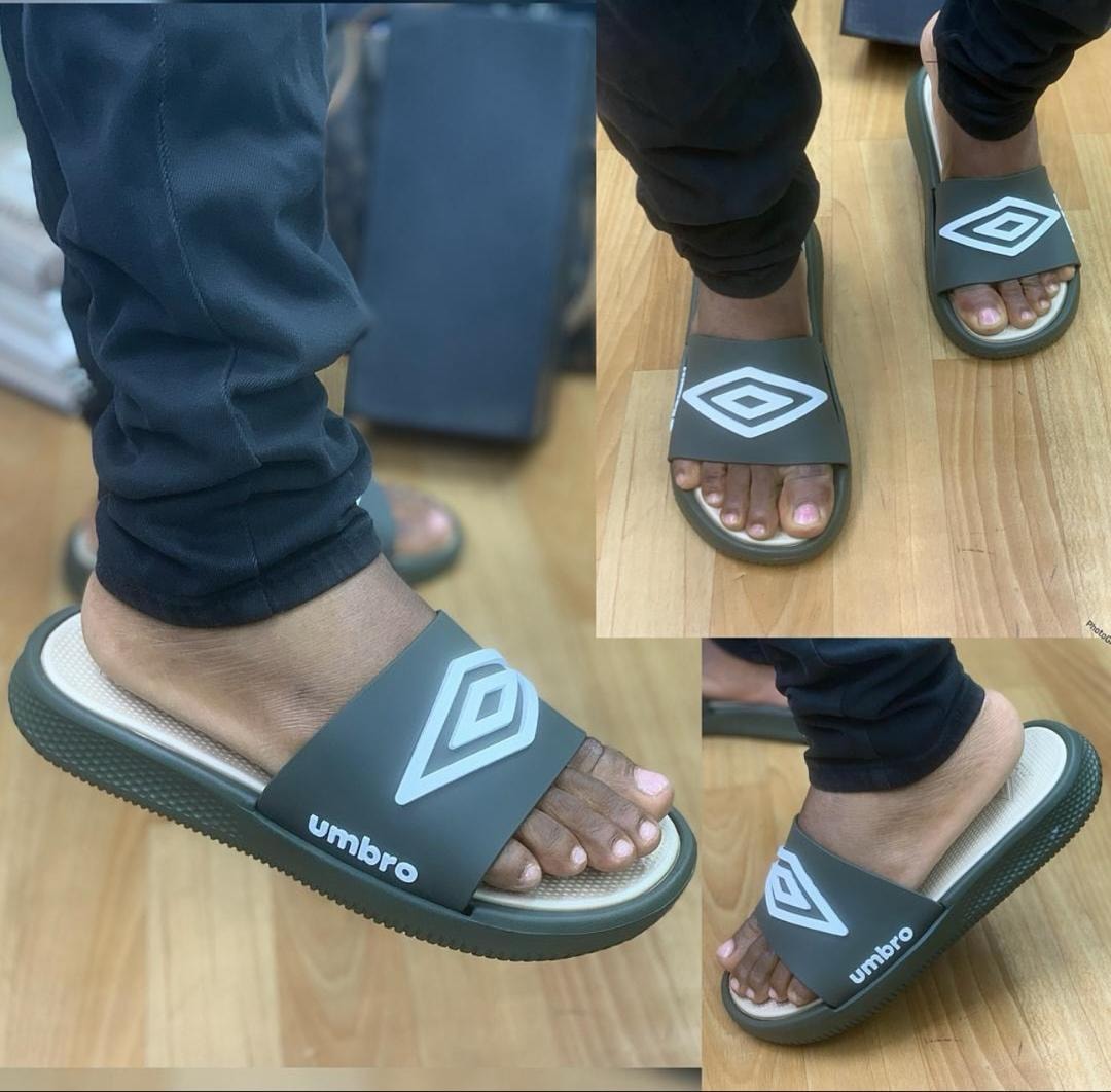 Olive Umbro slides on feet displaying the white logo and textured outsole.