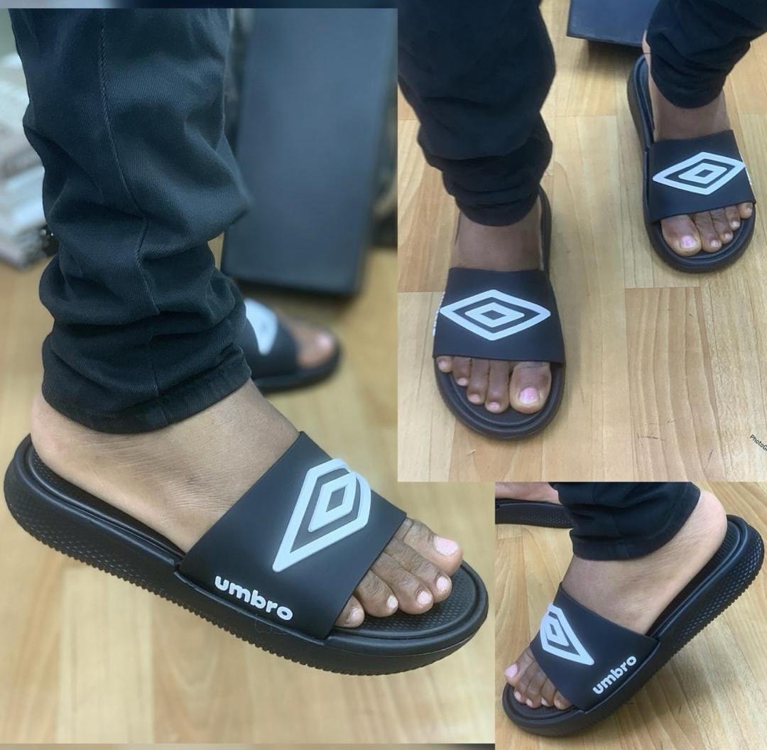 Black Umbro slides shown on feet from multiple angles including side and top views.