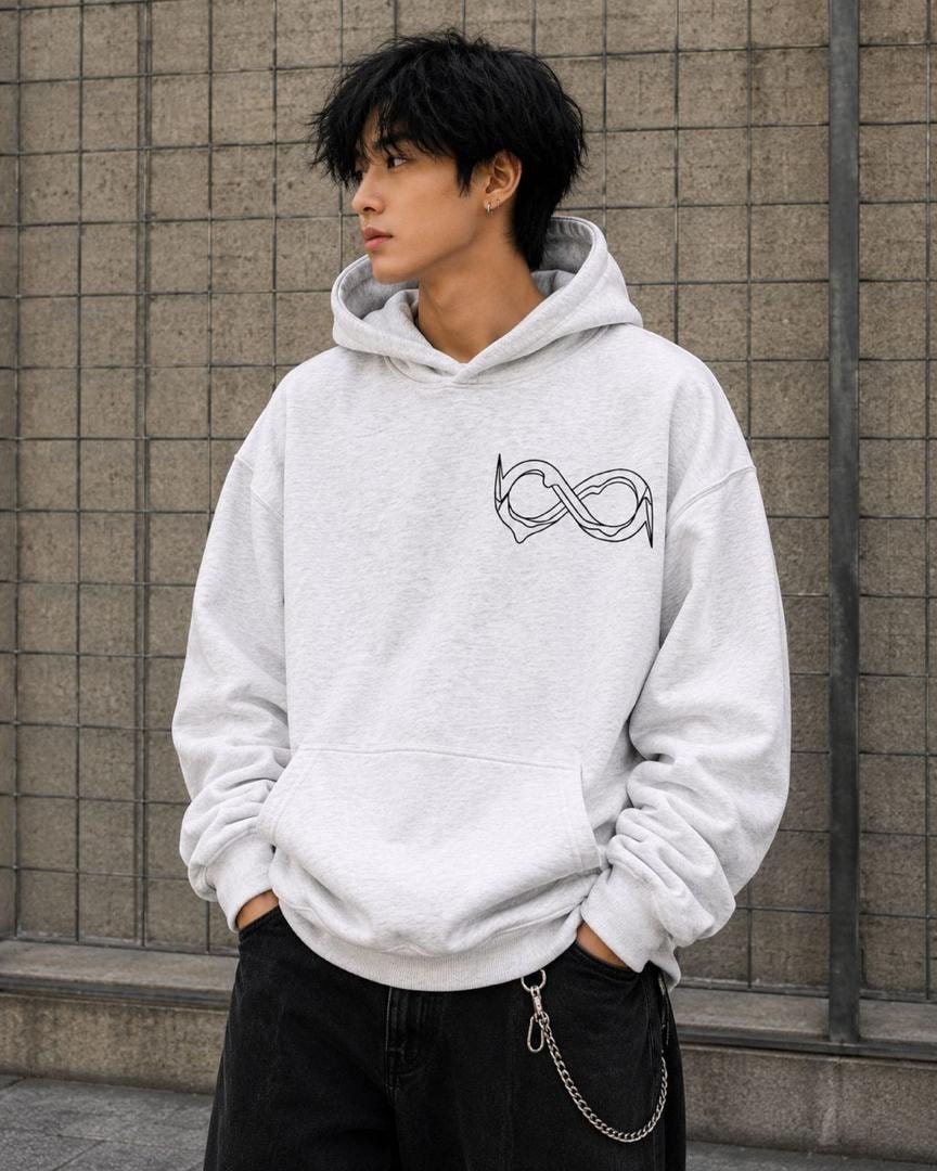 Man modeling light gray oversized hoodie with black infinity graphic on chest.