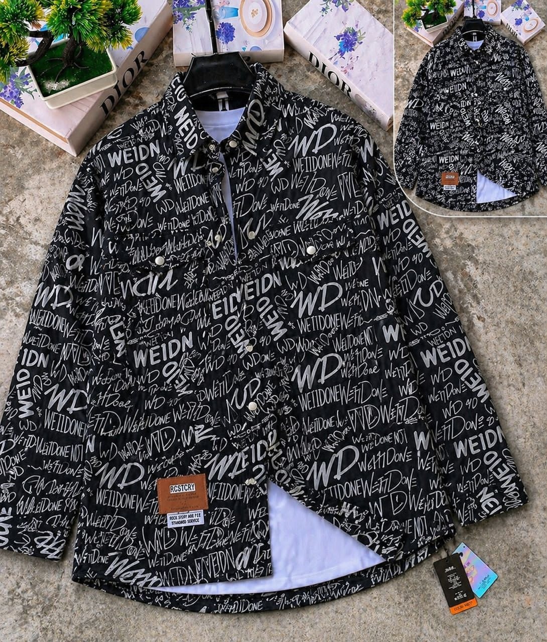 Black graffiti text denim jacket shown on hanger with white layer and inset back perspective.