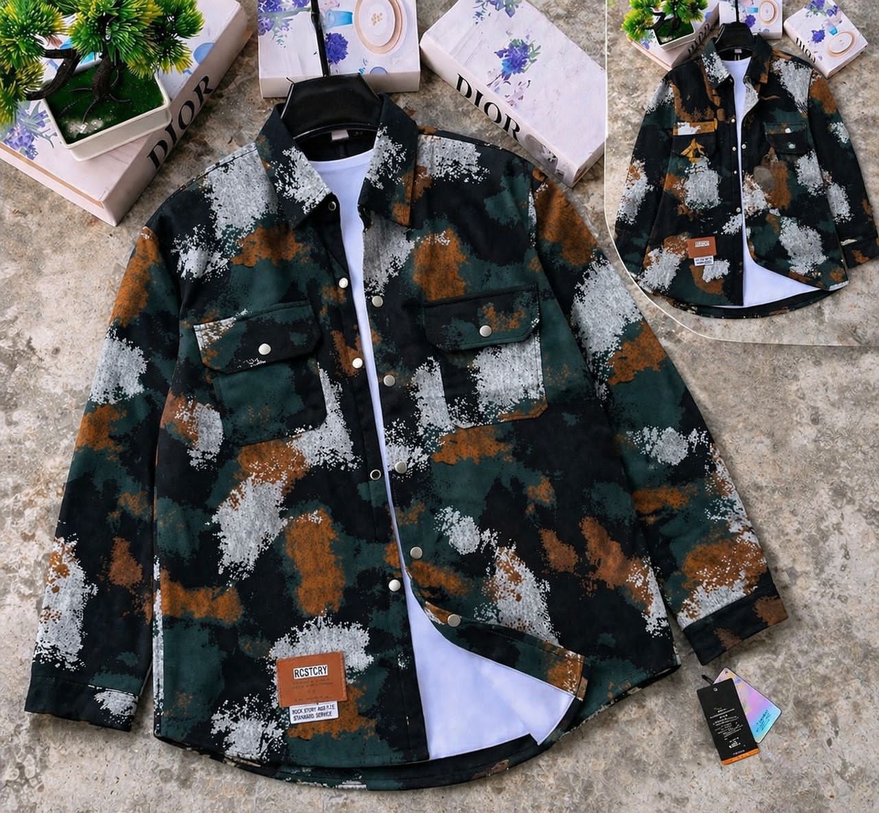 Green and brown splatter camouflage denim jacket on hanger over white tee, showing inset back view.