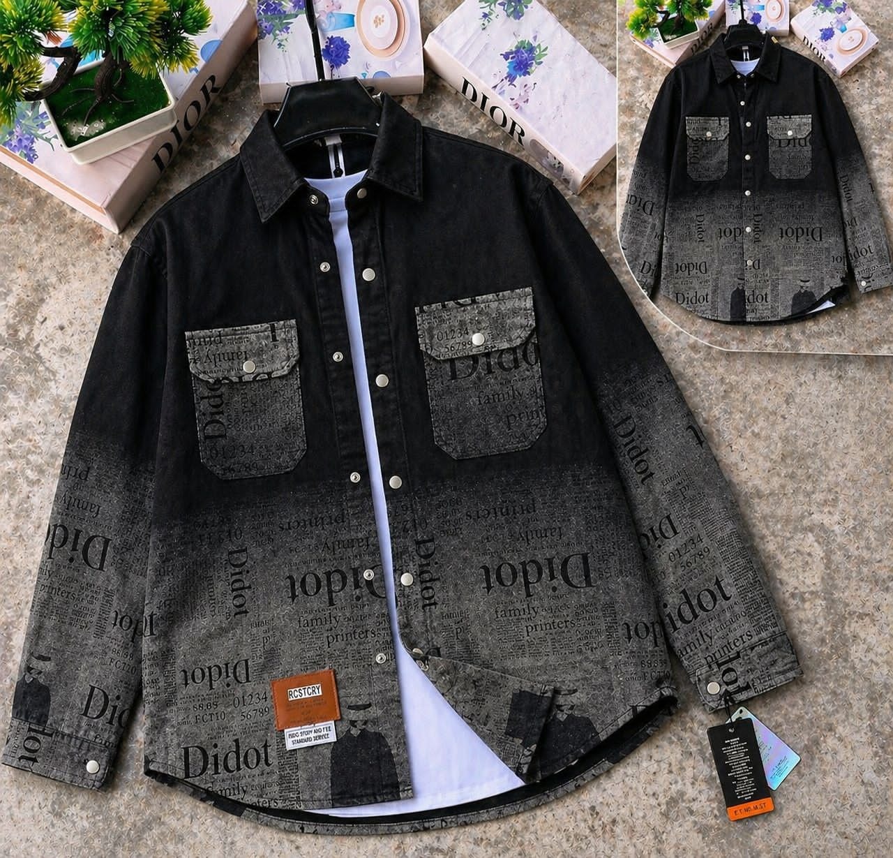 Black newspaper print denim jacket on hanger layered over white tee, with inset view and tags visible.