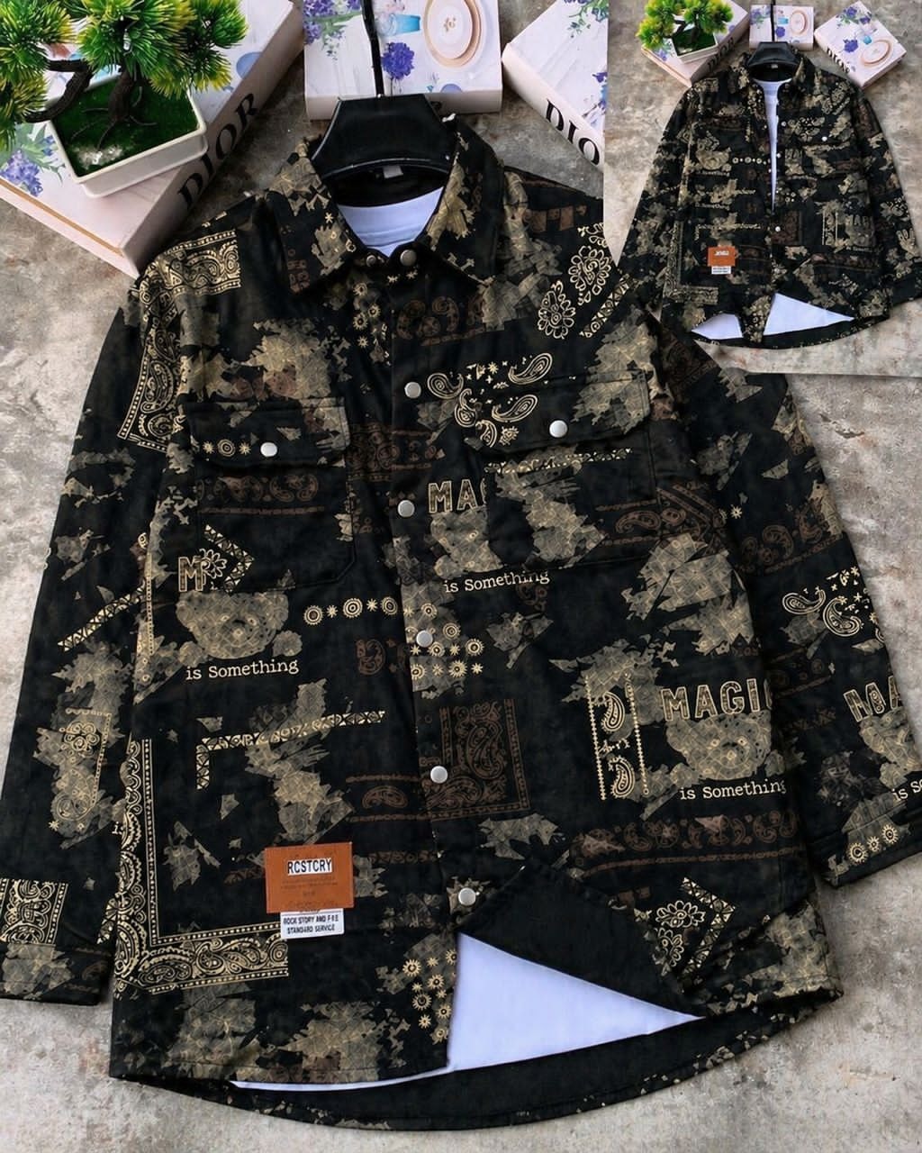 Black denim jacket with gold paisley and text prints, shown on hanger with white tee underneath and inset back view.