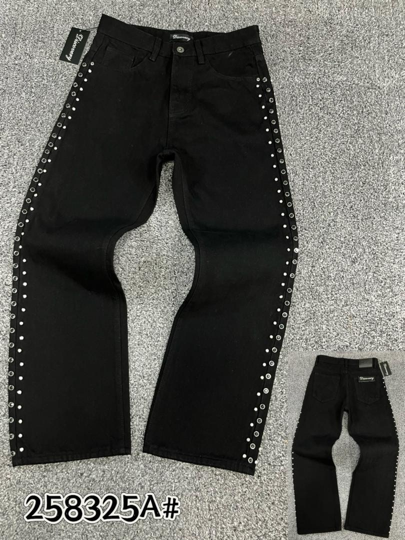 Front view of black baggy jeans with silver eyelets lining the outer leg seams.