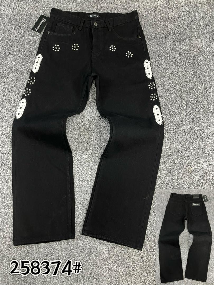 Black baggy jeans with white circular studded patterns on front and sides, flat lay view.