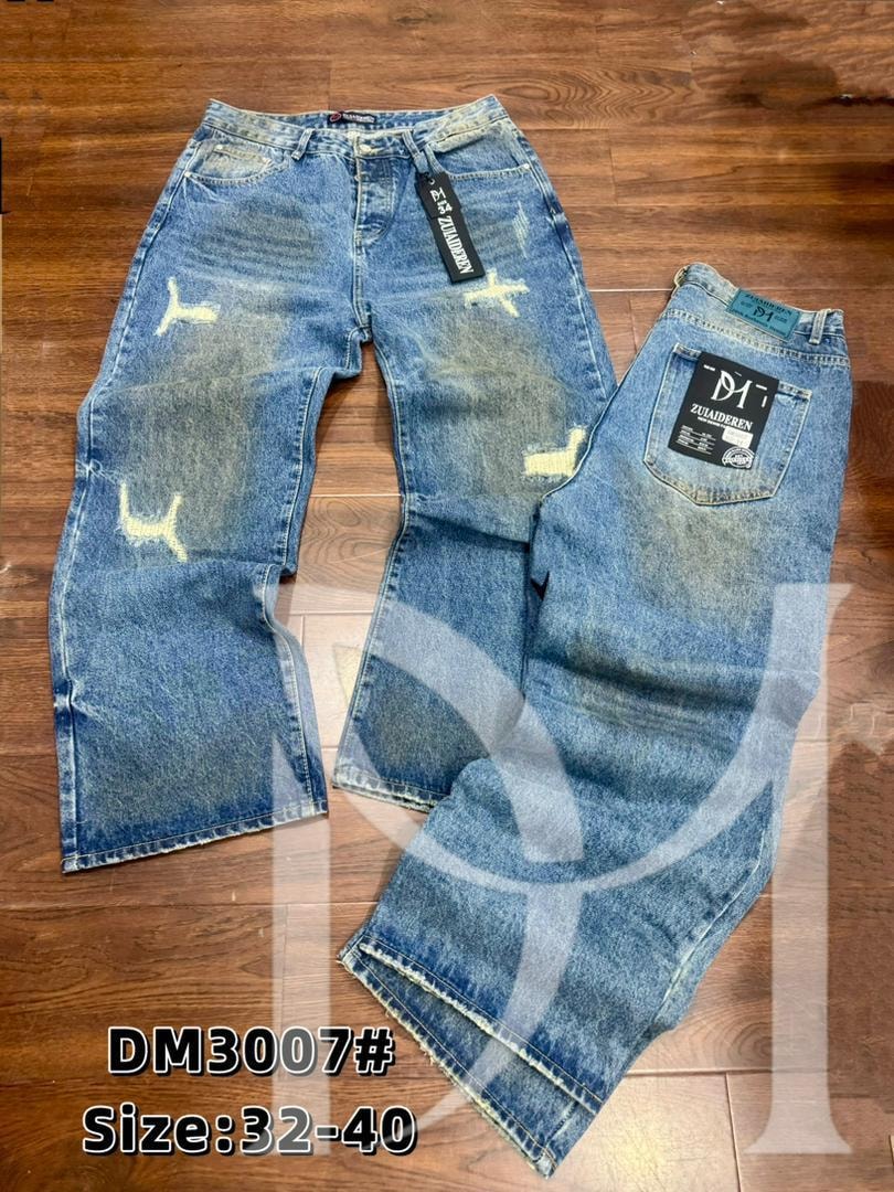 Front and back of blue baggy jeans with white marks, distressing and Zuaideren branding on wooden floor.