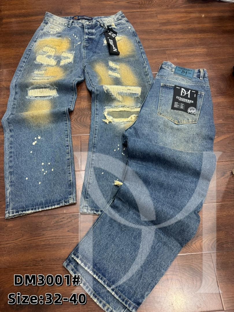Front and back views of blue distressed baggy jeans with yellow patterns, rips and tags on wooden floor.