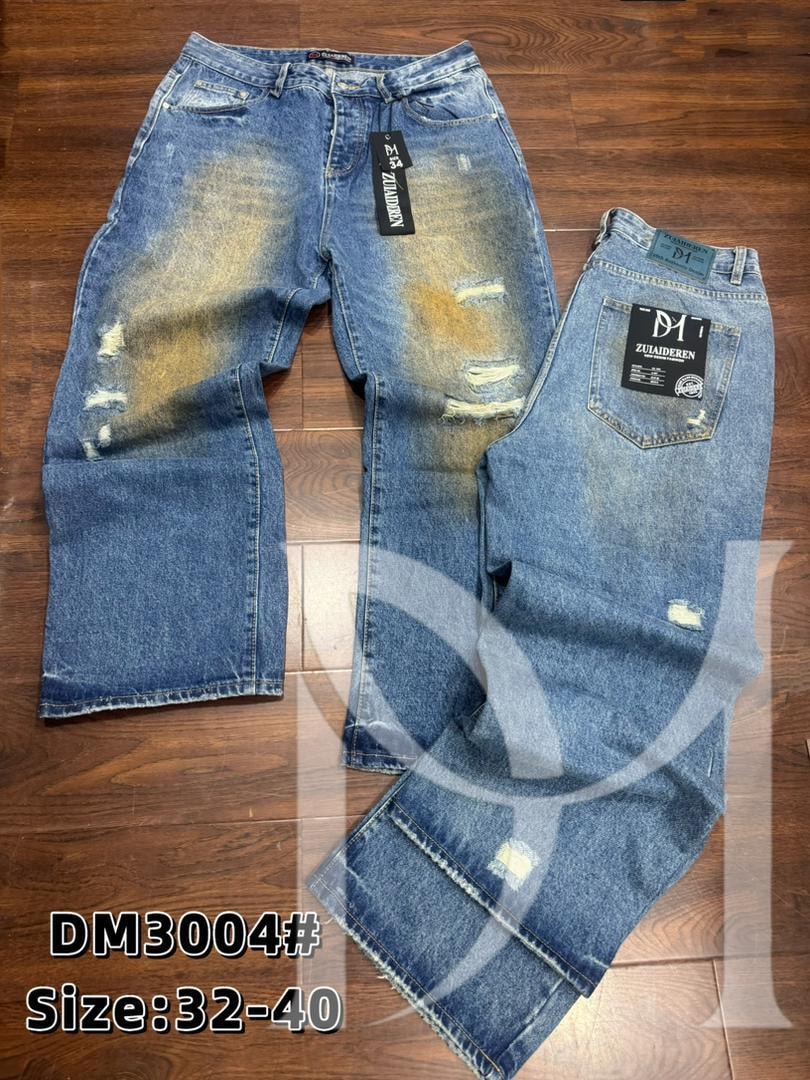 Front and back views of blue distressed baggy jeans with yellow bleach stains and rips on wooden floor.