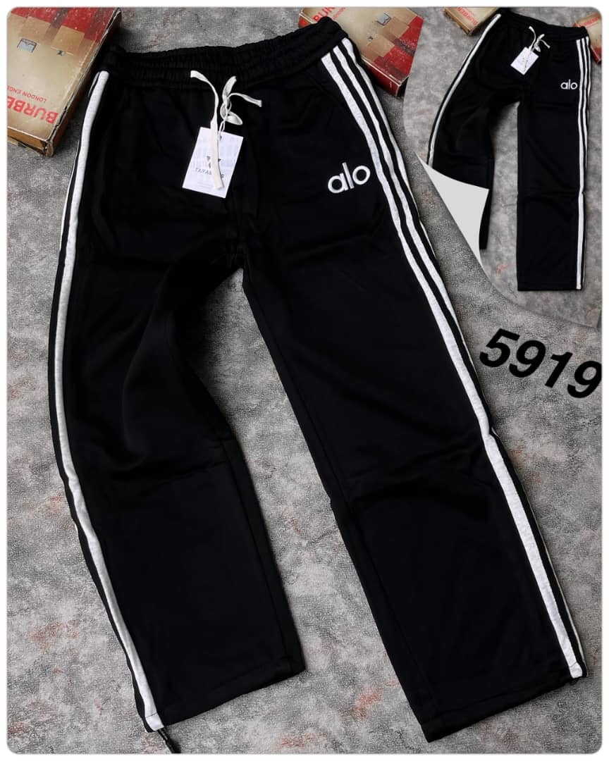 Black joggers with white straight side stripes, alo logo on thigh and TXFAMOUS tag.