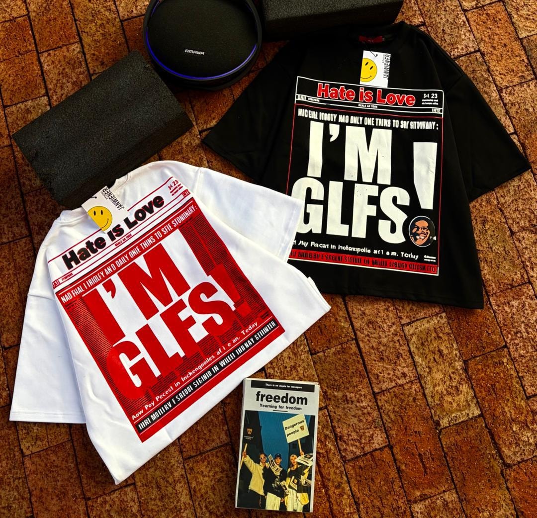 Flat lay of white and black Hate is Love I'm GLFS cropped tees with accessories.