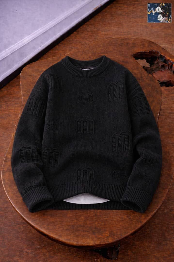 Black knit sweater with repeating embossed motifs across fabric.