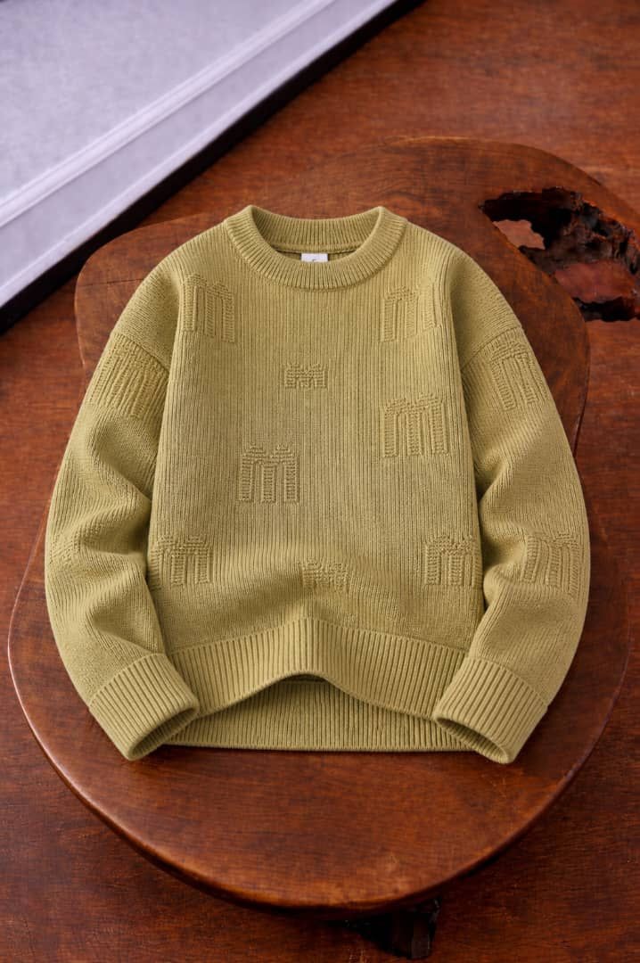 Olive knit sweater with repeating embossed motifs across fabric.
