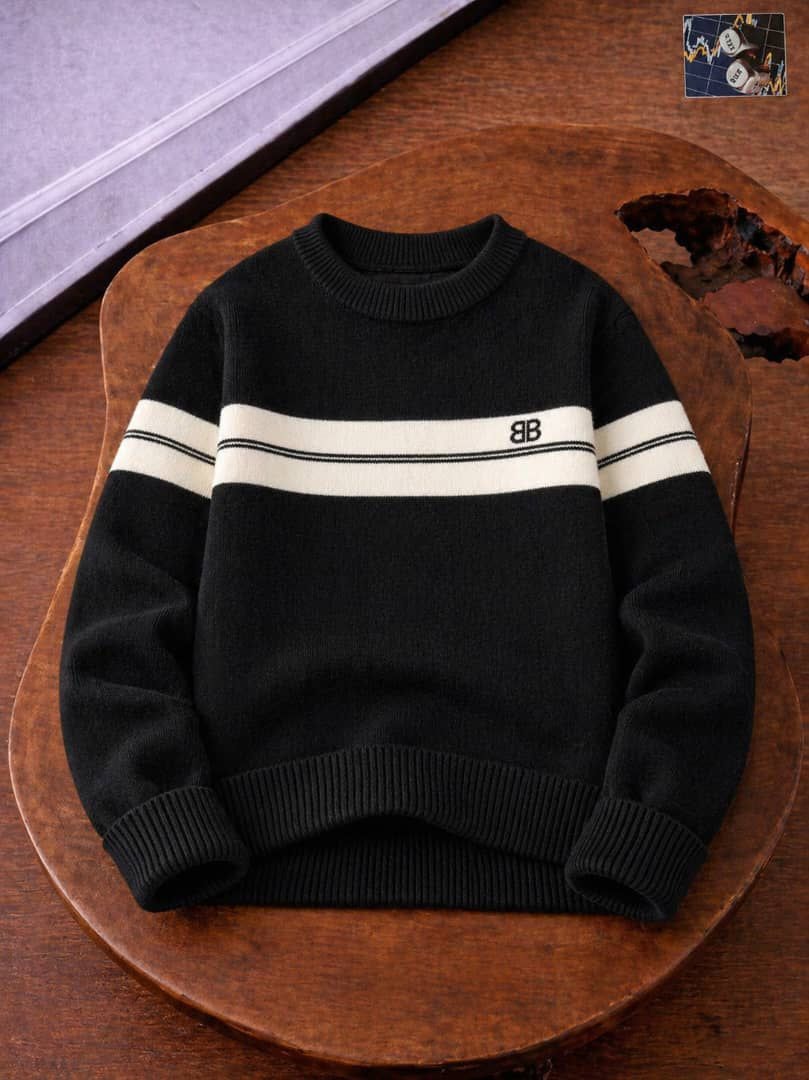 Black knit sweater with white stripes on sleeves and BB logo on wooden table.