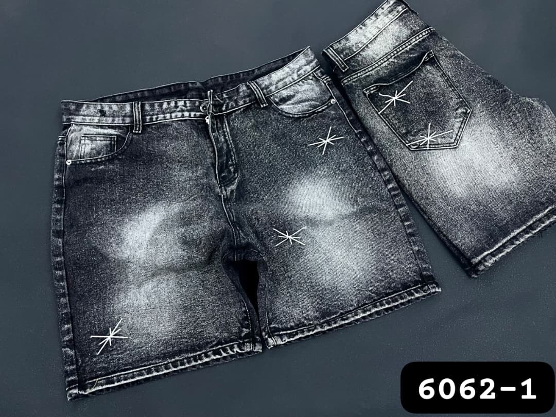 Black acid wash denim shorts with white star embroidery on front and back views.