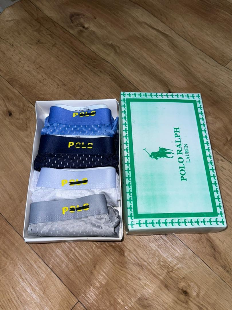 Polo Ralph Lauren 4-in-1 boxer pack in open box beside green branded packaging on wooden floor.
