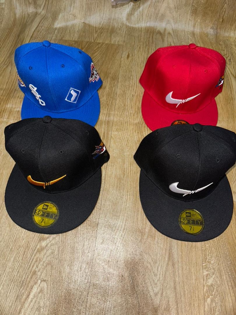 Assorted fitted face caps in blue, red and black with visible Nike swoosh, Polo and other embroidery.