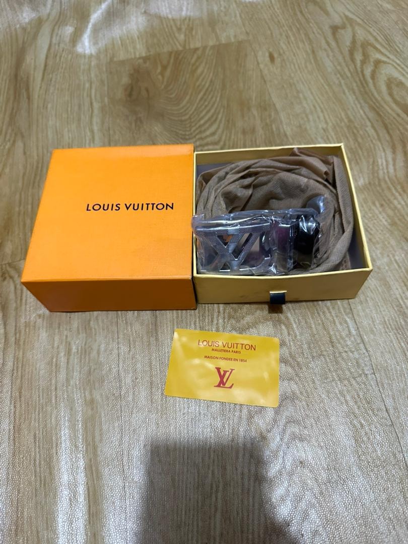 Louis Vuitton belt in orange box with yellow LV authenticity card on wooden surface.