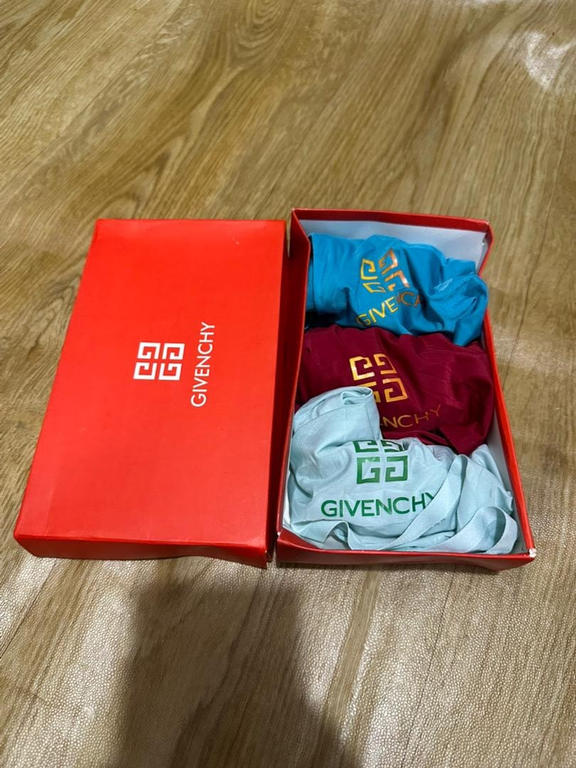 Red Givenchy box containing turquoise, maroon, and light blue GG logo boxers.