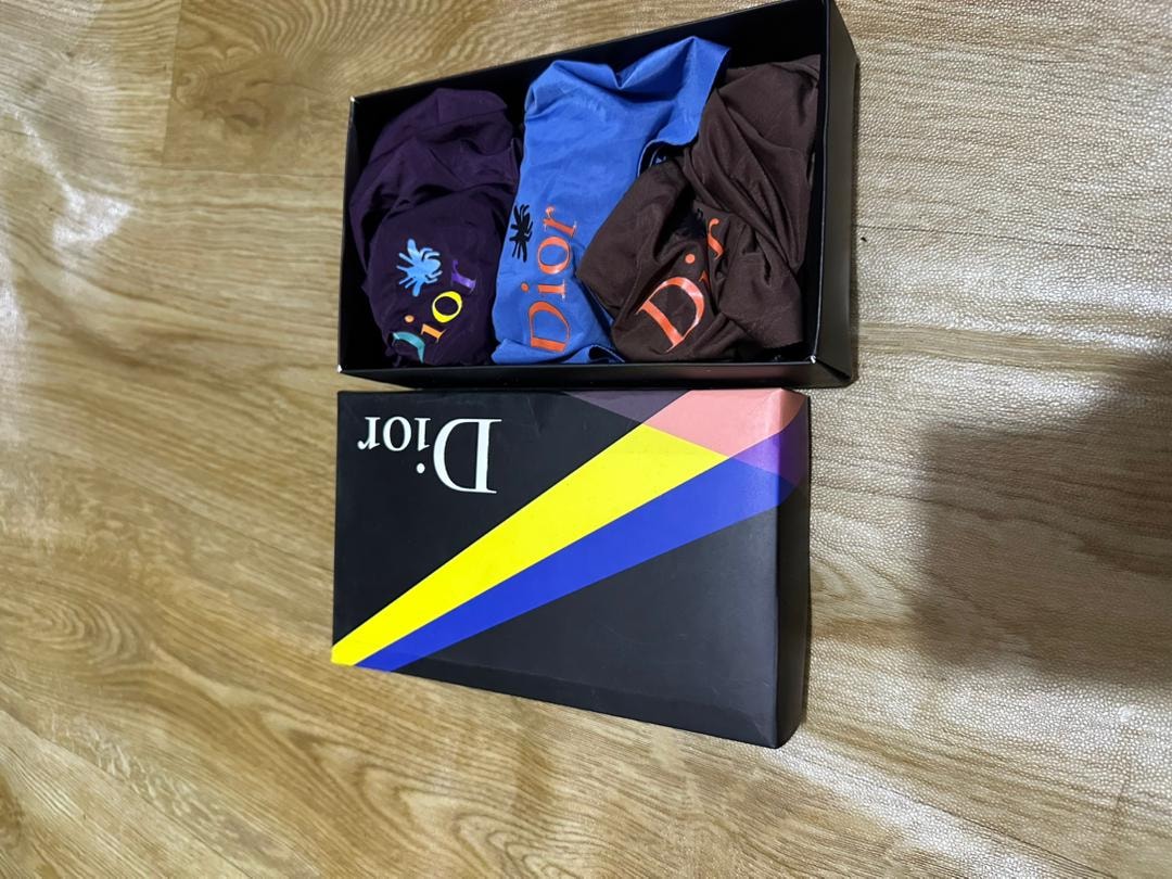 Black Dior box with purple, blue, and brown Dior logo boxer briefs.