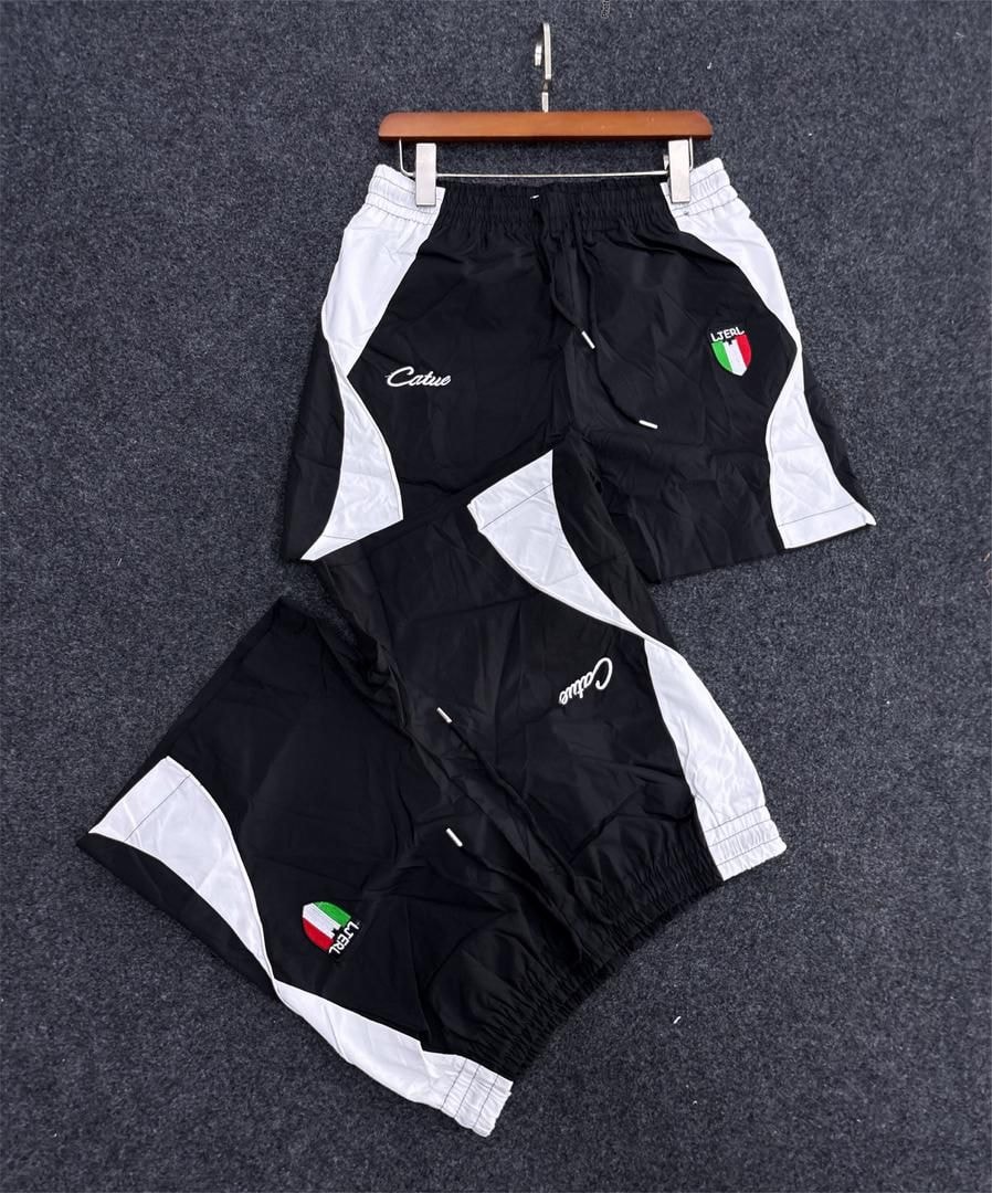 Black and white colorblock track shorts with script logo and Italian flag patch.