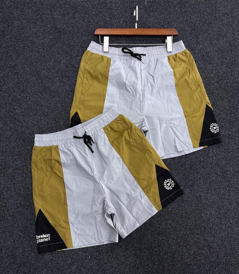 Yellow white and black Broken Planet shorts with text and circular logo.