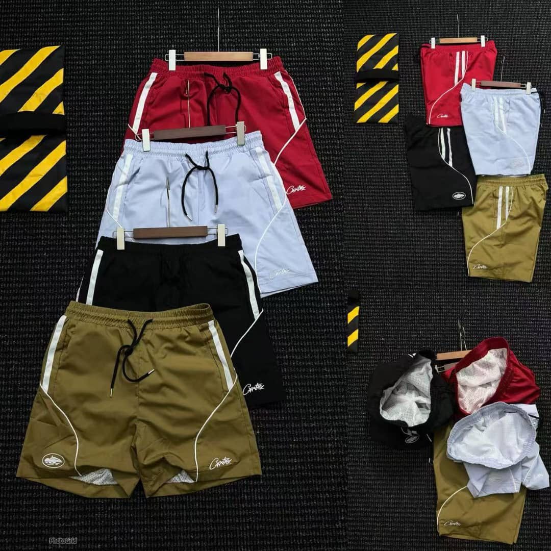 Assortment of Corteiz piped shorts in red, light blue, black and olive with white side stripes.