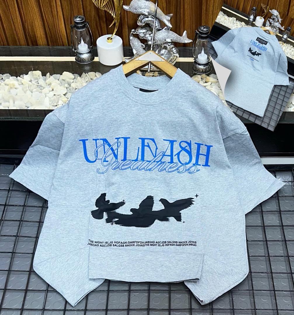Light gray Unleash Greatness oversized t-shirt with front graphic and back inset.