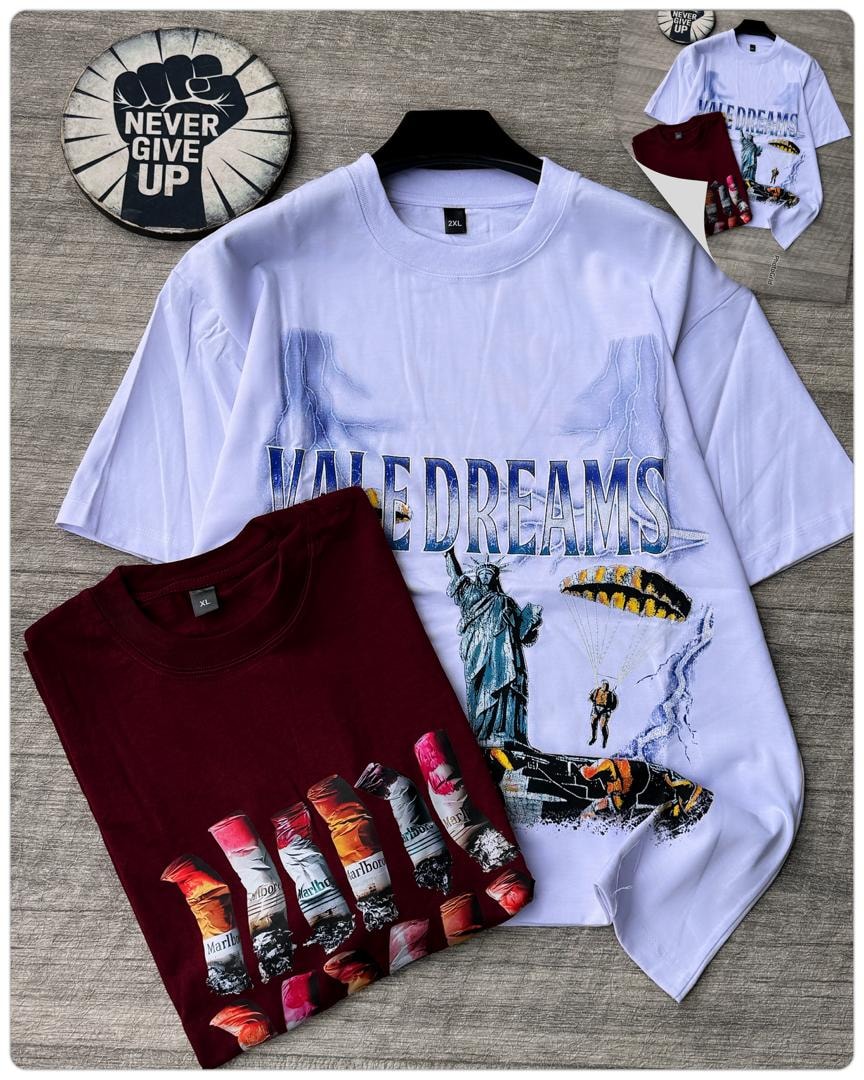 White VALE DREAMS oversized graphic t-shirt with Statue of Liberty and parachute design alongside maroon version.